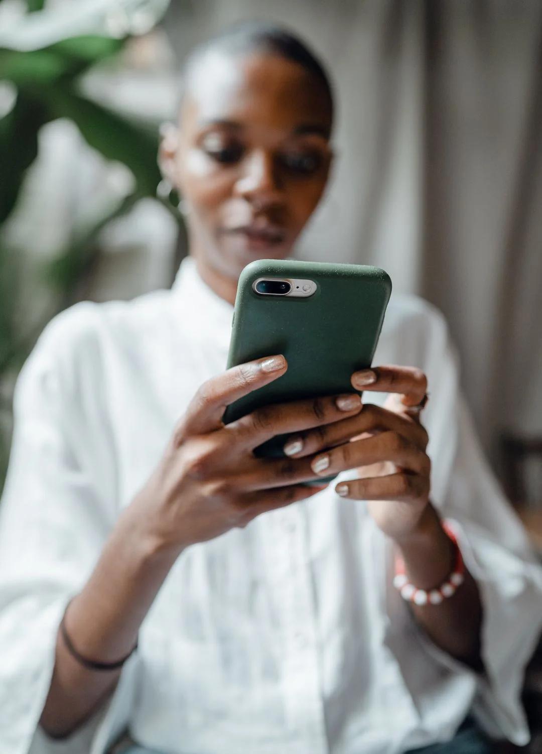 Woman in a white shirt answering a prompt on her smartphone at home, close up on the phone in her hands