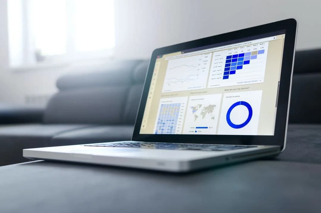 Open laptop on a couch displaying an analytics dashboard with charts, heatmaps, and a world map of survey data