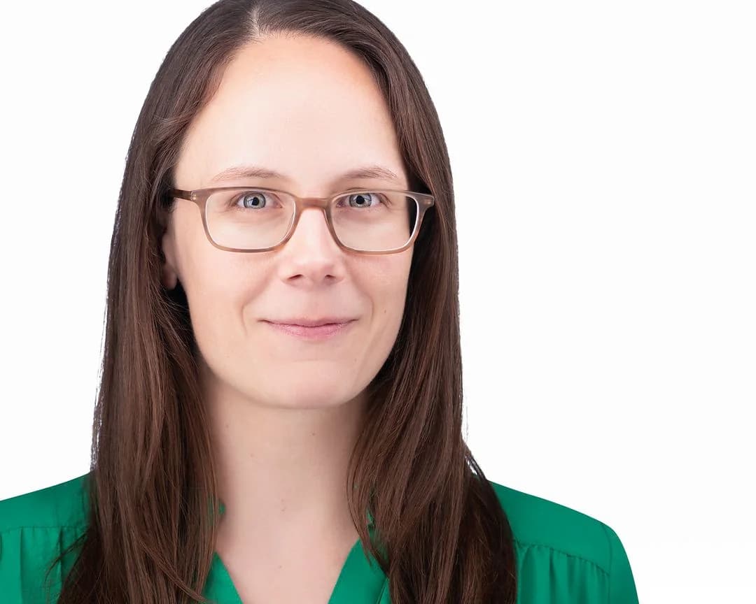 Portrait of Dr. Jessica Lougheed, wearing glasses and a green blouse, against a white background