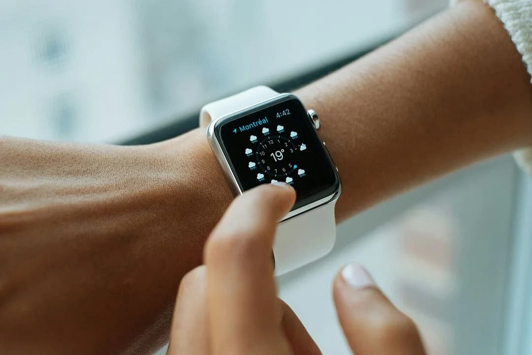 Person tapping a smartwatch on their wrist, a wearable that passively collects everyday behavioral data
