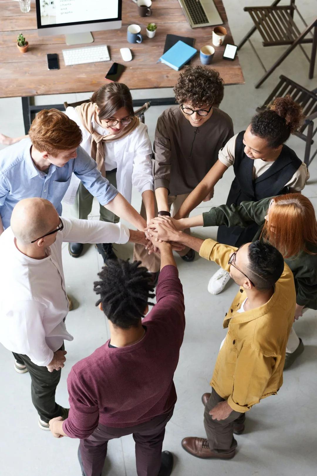 Diverse team of coworkers stacking hands together in a circle in a modern office
