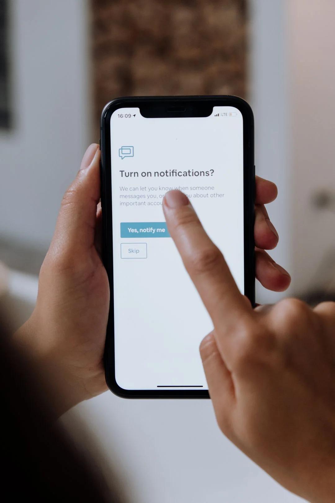 Hands holding a smartphone and tapping to enable push notifications on a turn-on-notifications prompt