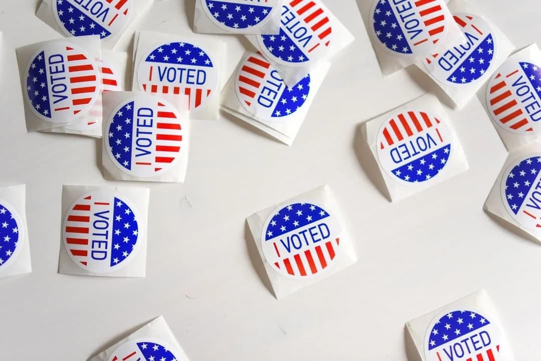Red, white, and blue I Voted stickers scattered across a white table after a US election