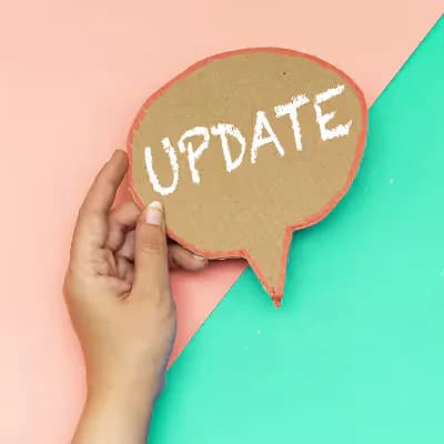 Hand holding a cardboard speech bubble reading Update against a pink and teal background