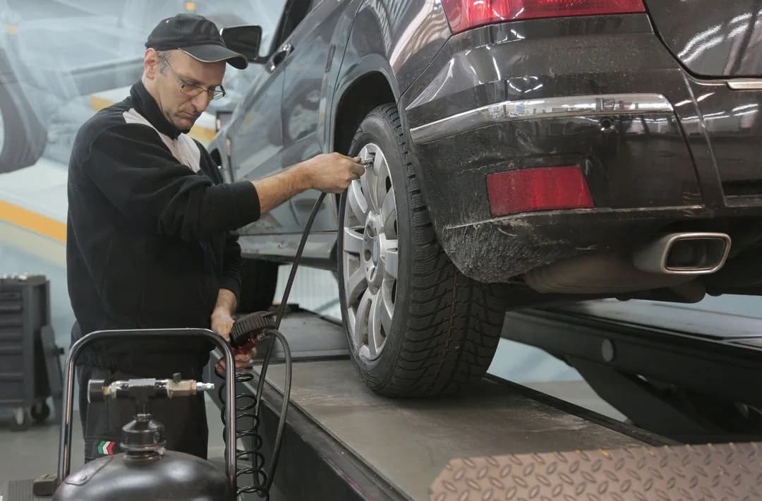 Mechanic checking the tire of a car raised on a lift in an auto workshop, an everyday workplace safety setting